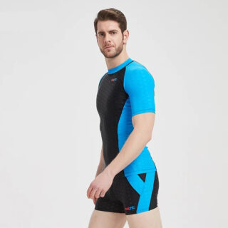 On voit un homma qui porte un maillot de bain deux pièces noir et bleu. Il est brun et barbu.