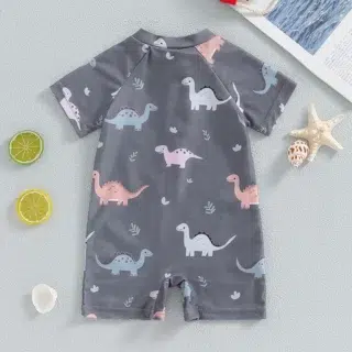 On voit un maillot de bain une pièce manches courtes zippé avec des motifs dinosaures.