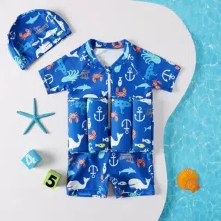 On voit un maillot de bain pour bébé une pièce avec une ceinture en flotteurs. Il est vert avec des imprimés dessin animé.