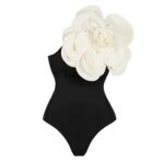 Maillot de bain noir avec fleur blanche sur fond blanc.