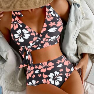 Buste de femme avec un maillot de bain noir avec des fleurs d'hibiscus blanches et roses