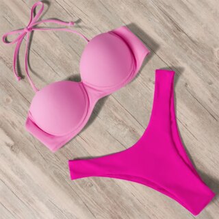 Maillot de bain rose deux pièces sur fond beige.