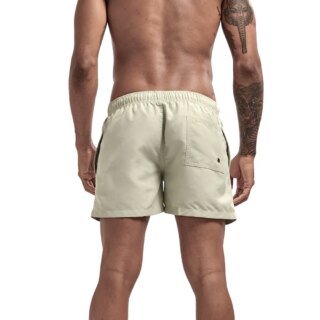 On voit un homme tatoué de dos, qui porte un short de bain beige respirant très simple.