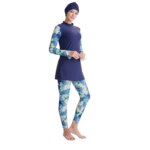 On voit une femme sur fond balnc qui porte un maillot de bain burkini bleu marine avec des motifs bleus nuages.