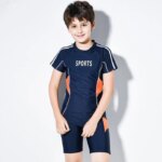 Garçon portant un maillot de bain deux pièces bleu sur fond blanc.