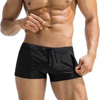 Photo d'un homme portant un maillot de bain shorty noir avec une petite poche à fermeture éclair verticale sur le devant gauche le tout sur fond blanc